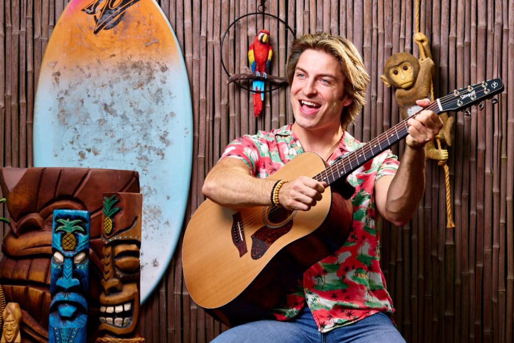 Brian Acker holding a guitar in Escape to Margaritaville