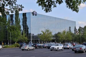 A glass-fronted office building with the Wizards of the Coast sign above a parking lot.
