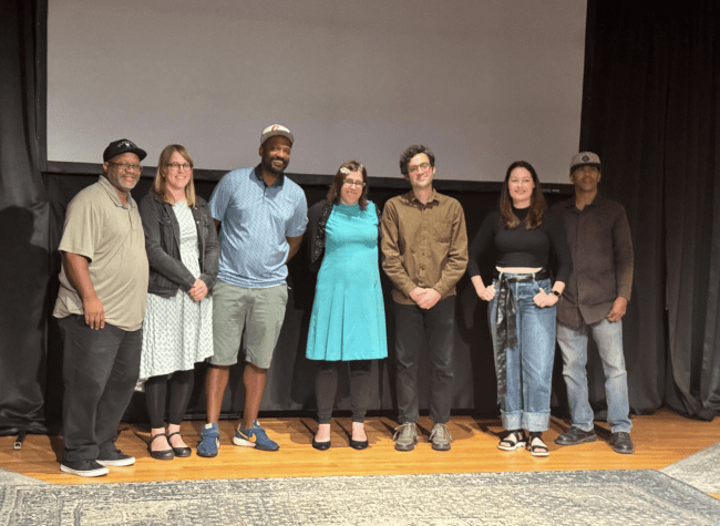 A group of Mental Filmness participants standing together in front of a cinema screen.